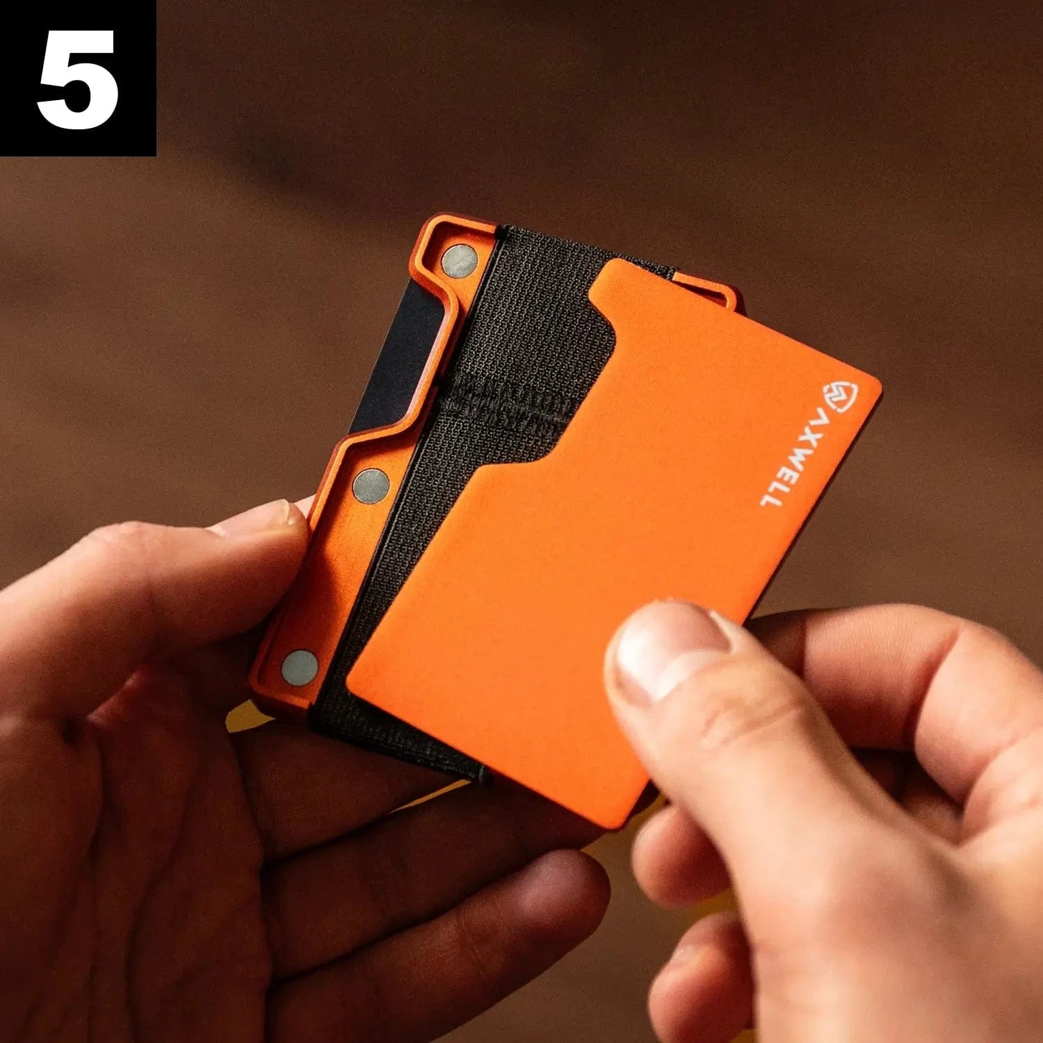 Person holding an orange Axxell wallet with a black strap