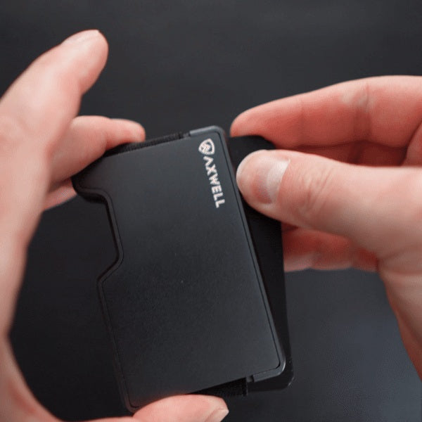 A finger pushes cards up through the Axwell wallet's larger opening.